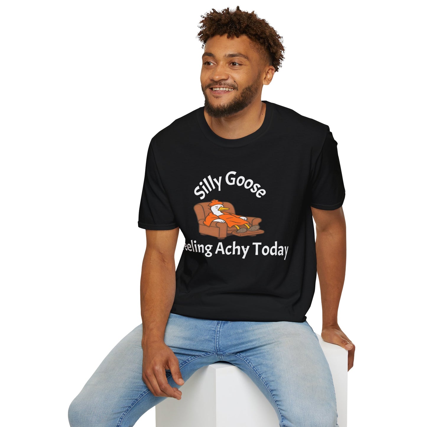 Man wearing a black t-shirt with a silly goose graphic and text, sitting on a white stool against a white background.