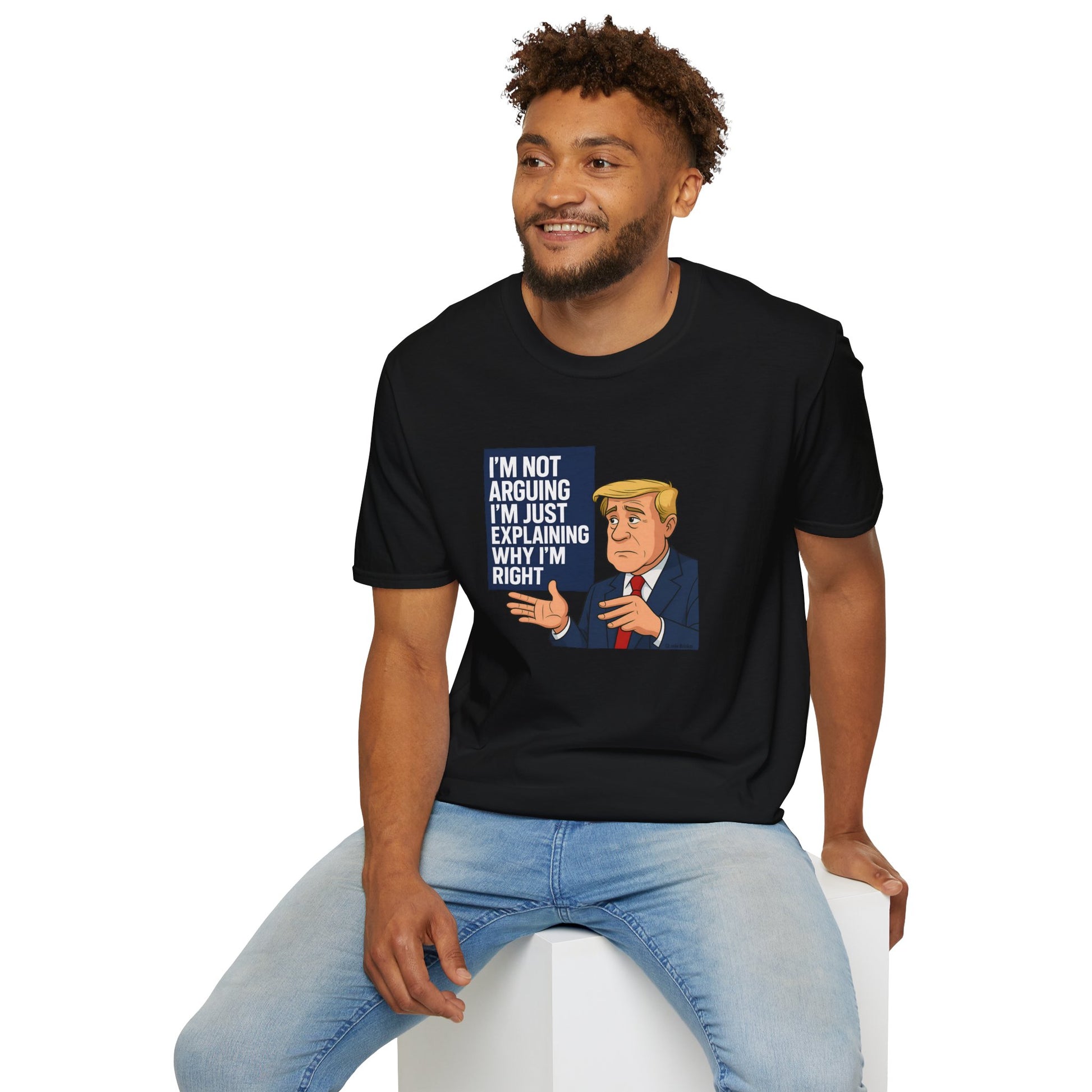 Man wearing a black t-shirt with a graphic and text, sitting on a white stool against a white background.