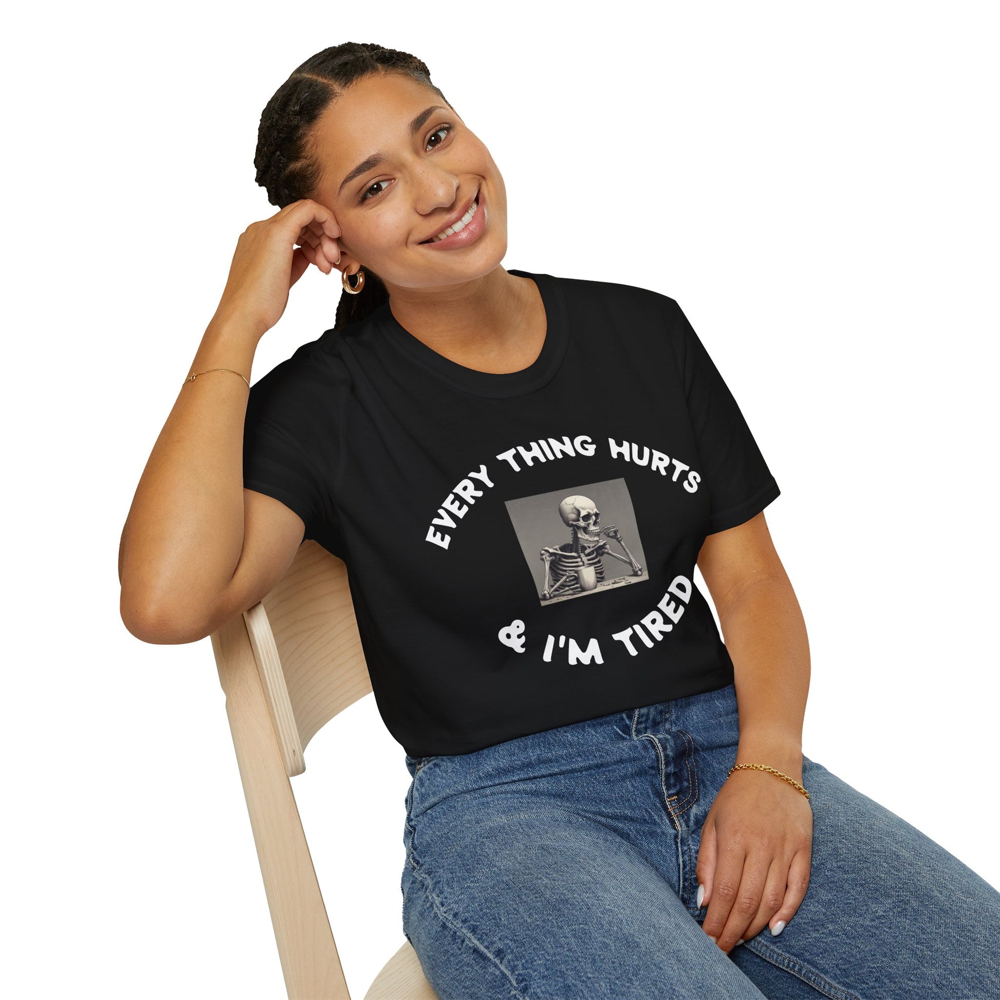 Person wearing a black t-shirt with text and a skeleton graphic, sitting on a chair.