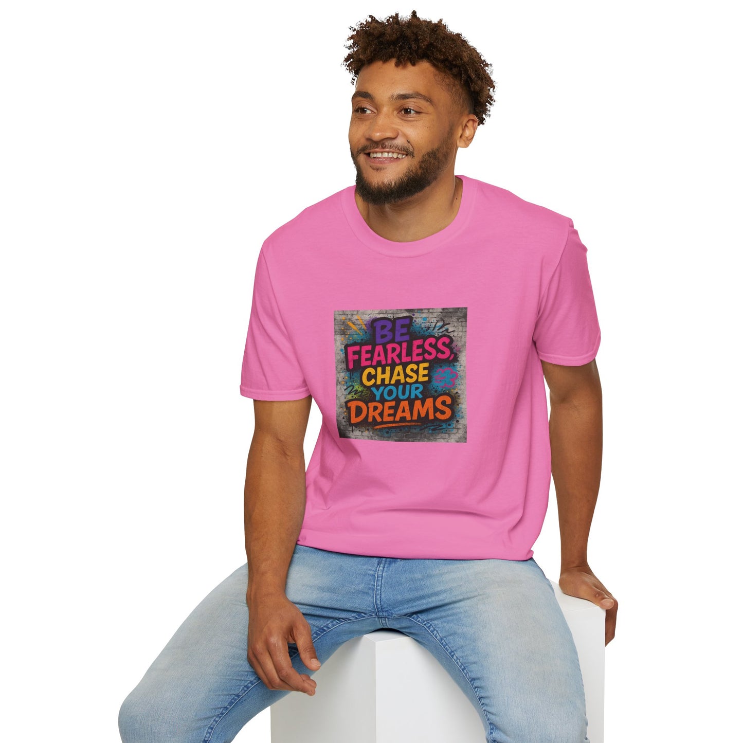 Man wearing a pink t-shirt with motivational quote sitting on a white stool against a white background