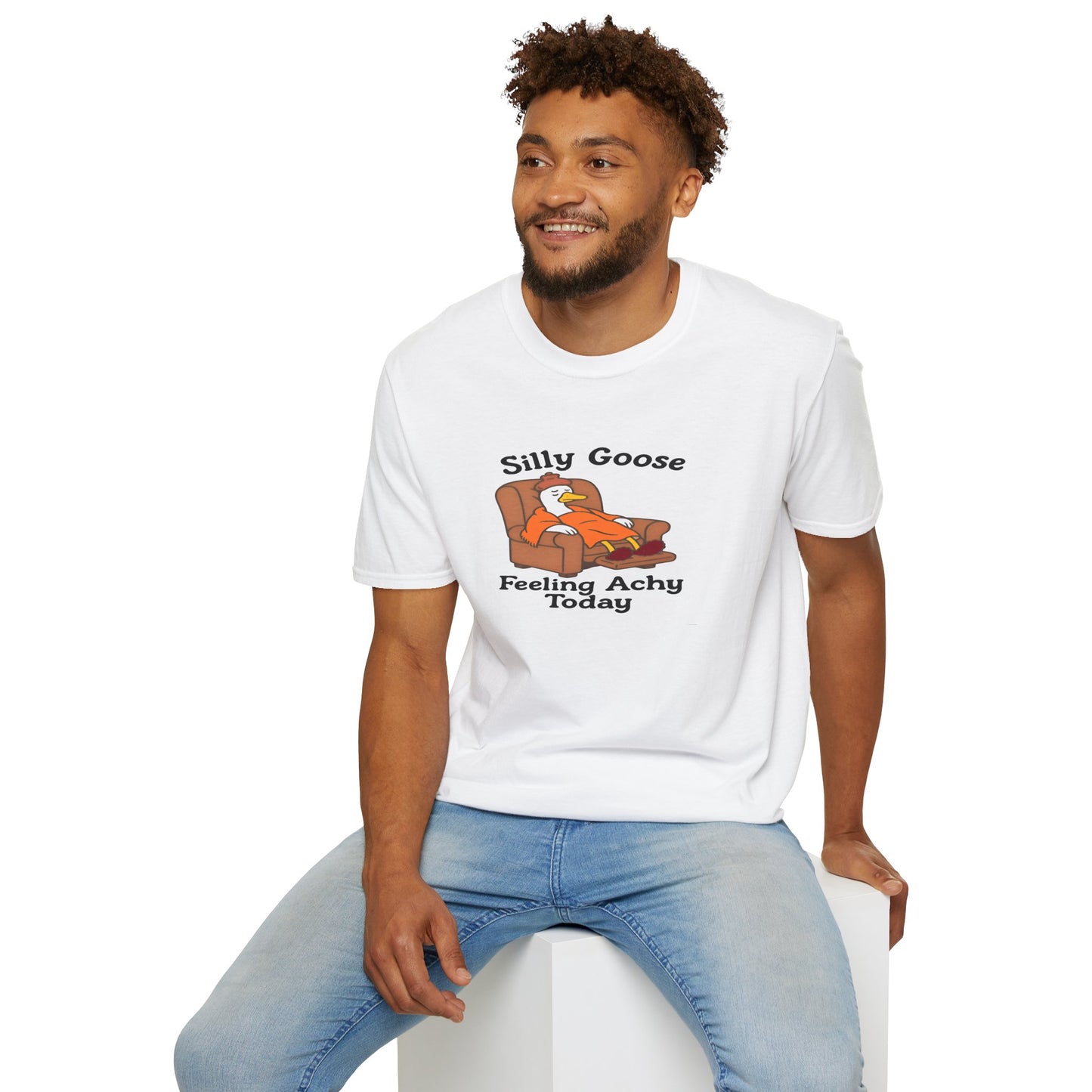 Man wearing a white t-shirt with a silly goose graphic and text, sitting on a white stool against a white background.
