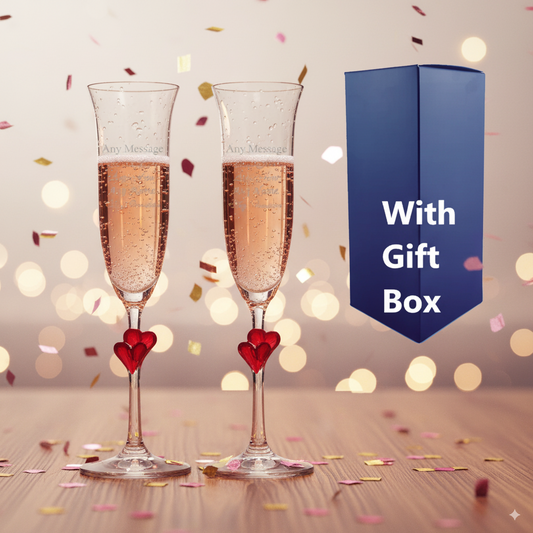 Two engraved L AMOUR  champagne flutes with a heart-shaped candle and a gift box on a festive background.