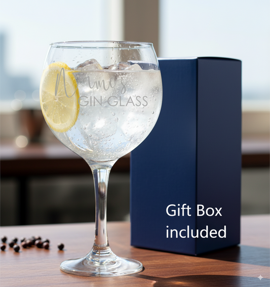 Personalised Gin glass with lemon wedge and ice, accompanied by a blue gift box on a wooden surface.