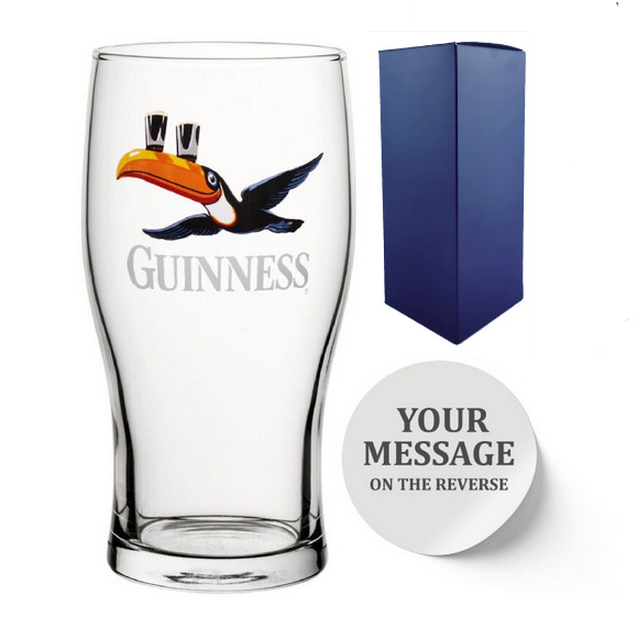 Clear Guinness beer glass with toucan logo and a blue gift box on a white background