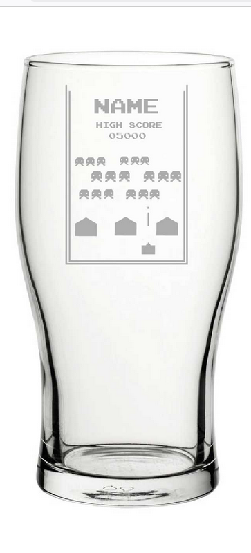 Clear  pint glass with engraved text and space arcade game symbols on a white background